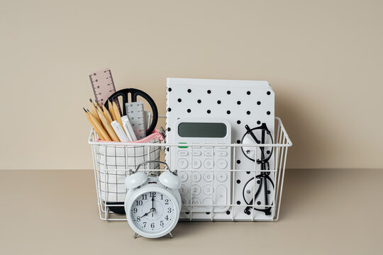 Organizer with school or office stationery supplies and alarm on beige background. Organizing and Storage office supplies.