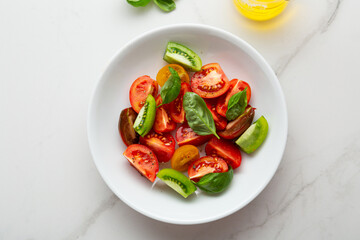 Overhead view of fresh summer tomatoes salad with basil