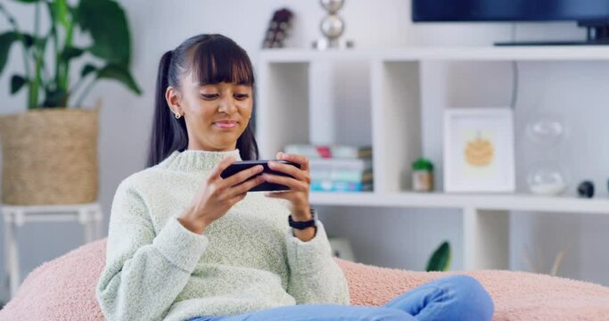 Trendy female gamer using phone to stream an online game. A young confident woman playing multiplayer on an interactive video gaming app and doing a happy fist pump gesture after winning