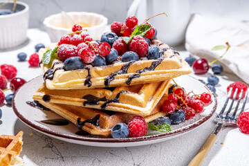 Sweet waffles with berry. Homemade summer breakfast belgian waffles with raspberries, blueberries, strawberry honey and chocolate dip sauce, copy space