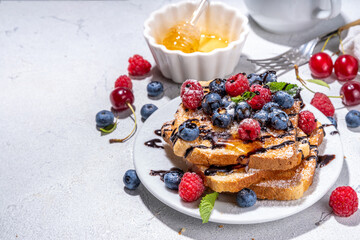 Summer breakfast with french toast. Baked with toasts with berries (blueberries, strawberries) and honey, traditional morning sweet dessert with fresh ripe berry