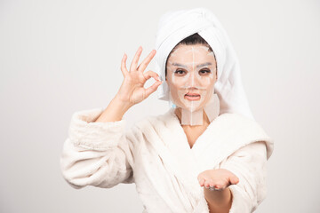 Woman wearing bathrobe and towel with facemask