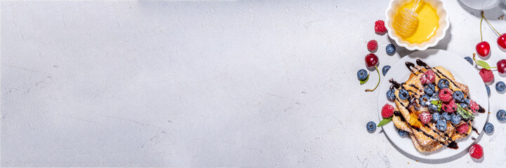 Summer breakfast with french toast. Baked with toasts with berries (blueberries, strawberries) and honey, traditional morning sweet dessert with fresh ripe berry