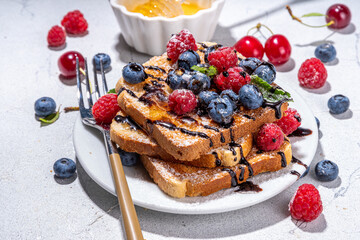 Summer breakfast with french toast. Baked with toasts with berries (blueberries, strawberries) and honey, traditional morning sweet dessert with fresh ripe berry
