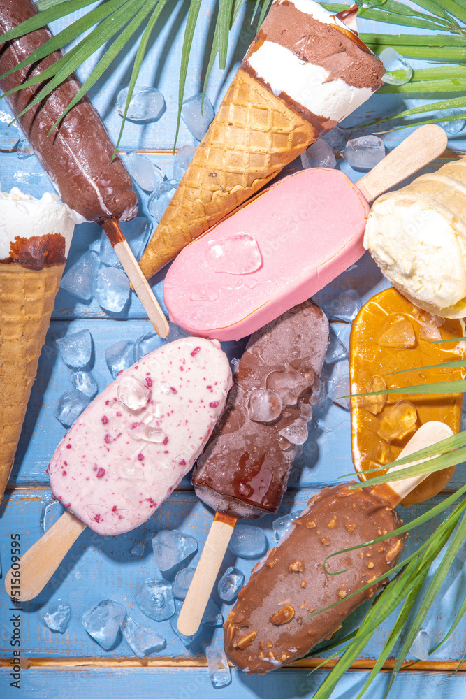 Wall mural Set of various ice cream popsicle on black background. Assortment of icecream cones and popsicles on wooden blue beach background with tropical palm leaves top view flatlay copy space