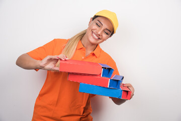 Delivery woman with yellow hat holding pizza boxes on white background