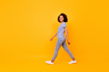 Full length photo of charming positive girl walk have good mood isolated on yellow color background