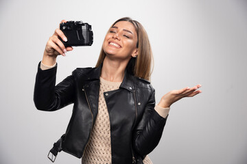 Blonde girl in black leather jacket taking her selfies with a camera