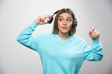 Blonde girl in blue sweatshirt taking out the headphones to hear the people around
