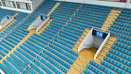 Empty audience seats in the giant stadium. Drone aerial view. Flying around empty stadium, blue audience auditorium inside during pandemic period.  Sports business and covid-19 concept b-roll footage. - Powered by Adobe