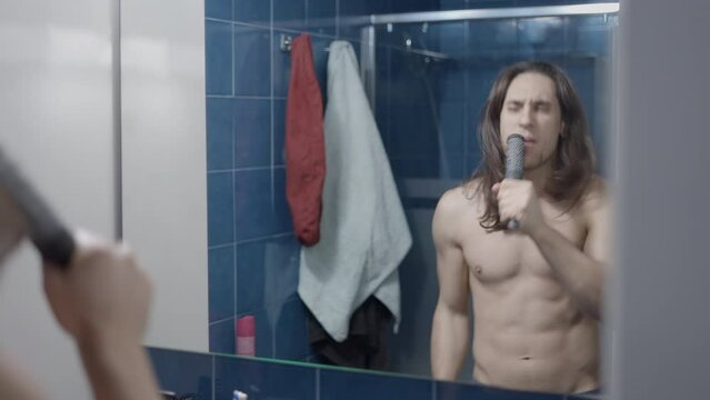 Long-haired Man Singing In Front Of A Bathroom Mirror With A Hairbrush As A Microphone - Middle Shot