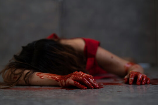Asia woman in red dress lying on the floor with blood and knife at crime scene. Concept of people,.the criminal or murderer. Blood of victim on the floor and body. Bloody dead woman on the ground.