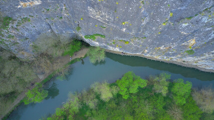 Aerial photography from a drone. View of green fields, rocky mountains and a river in a valley