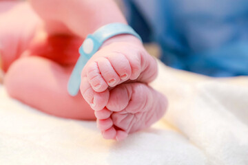 Newborn baby feet in hospital bed lying on their back with hospital bracelets on his feet