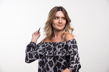 Young woman looking thoughtful while holding telephone on white background