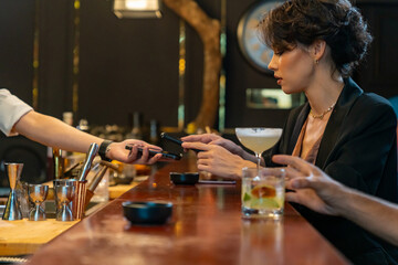 Caucasian woman using mobile banking application on smartphone scan QR code making online payment while hangout party at restaurant bar. Electronic banking and Contactless payment technology concept.