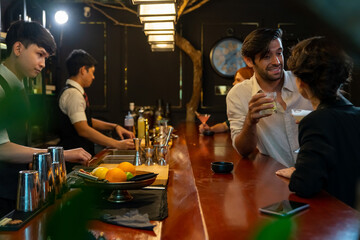 Group of People man and woman enjoy hangout nightlife meeting party with alcoholic cocktail drink at luxury restaurant bar. Male bartender preparing alcoholic drink serving to customer at nightclub