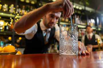 Professional male bartender preparing and serving cocktail drink to customer on bar counter at luxury nightclub. Barman making mixed alcoholic drink for celebrating holiday party at restaurant bar.