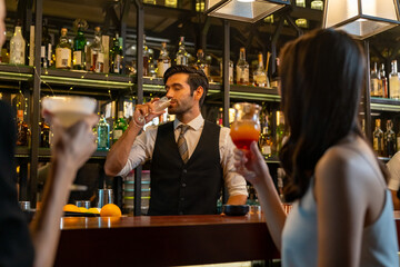 Attractive woman friends enjoy hangout nightlife meeting party and drinking alcoholic cocktail at luxury restaurant bar. Male bartender talking and celebrating holiday event with customer at nightclub