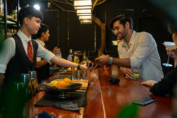 Caucasian man using mobile banking application on smartphone scan QR code for making online payment while hangout party at restaurant bar. Electronic banking and Contactless payment technology concept