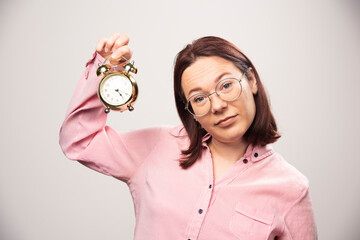 Young woman model holding an alarm clock on a white background