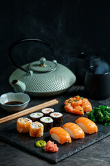 Sushi Set nigiri and sushi rolls, on black stone slate on black background