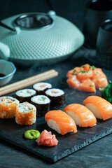 Sushi Set nigiri and sushi rolls, on black stone slate on black background