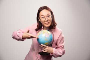 Portrait of woman showing an Earth globe on a white background