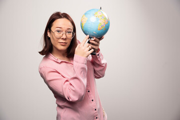 Portrait of woman showing an Earth globe on a white background