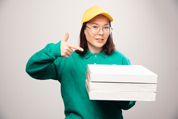 Deliverywoman showing cardboards of pizza on a white background