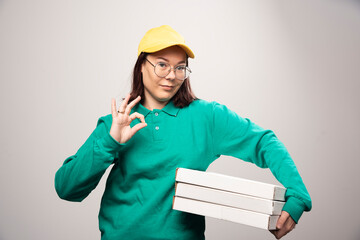 Deliverywoman carrying cardboards of pizza on a white background