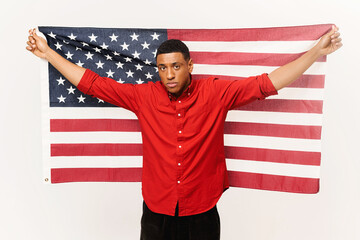 Serious African-American guy holding in hands american flag isolated over white background, multiracial foreign student man holding US flag, independence day celebration, holiday