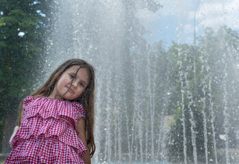 Fototapeta na wymiar Cute teenage girl against blurred background of water jets of fountain