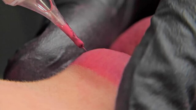 Close-up of a permanent makeup procedure. A needle pierces the lips and injects paint under the skin. Macro