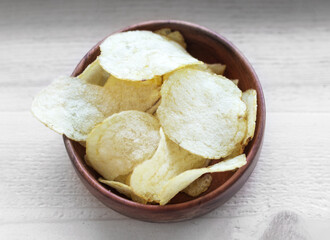 Close-up of potato chips or crisps in bowl on the wooden background