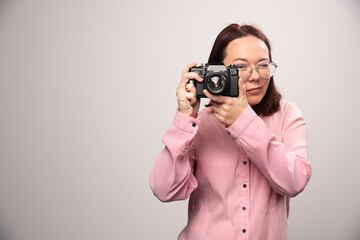 Woman taking a picture with camera on white background