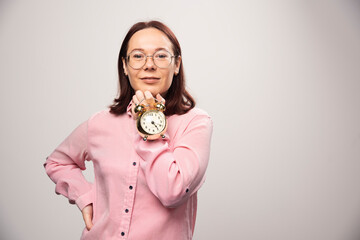 Fototapeta na wymiar Young woman model holding an alarm clock on a white background