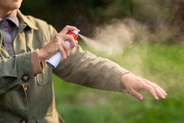 health care, protection and people concept - woman spraying insect repellent or bug spray to her...