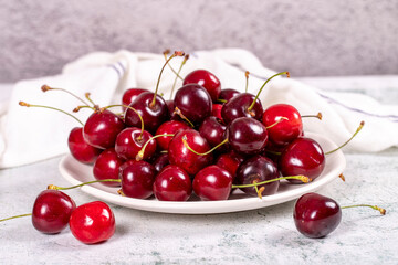 Naklejka na ściany i meble Fresh cherry. Ripe cherries in a plate on a stone background. Bulk cherries. close up