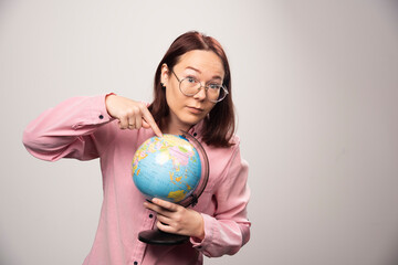 Portrait of woman showing an Earth globe on a white background