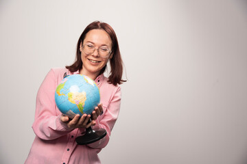 Portrait of woman looking on an Earth globe on a white background