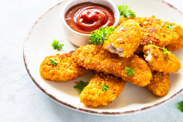 Chicken nuggets with ketchup sauce at white table.