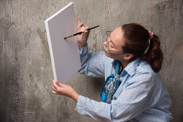 Woman sitting and draw something in canvas with brush on marble background