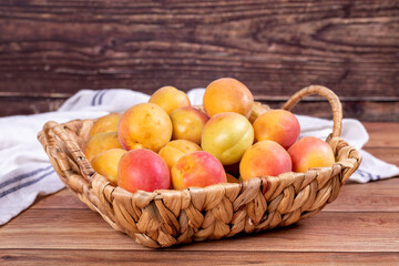 Fresh apricots. Ripe apricots in basket on wood background. Bulk apricots. close up