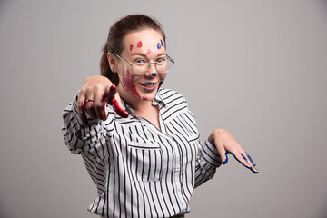 Woman with paints on her face and glasses on gray background