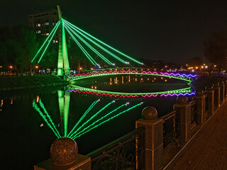 Bridge with colored lights. Night city Kharkiv. River and dark background. Urban. Ukraine