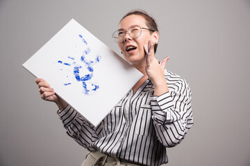 Woman with canvas of picture her hand on gray background