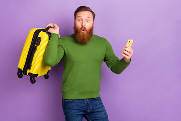 Portrait of handsome trendy amazed guy using device buying tour tickets book isolated over bright violet lilac color background