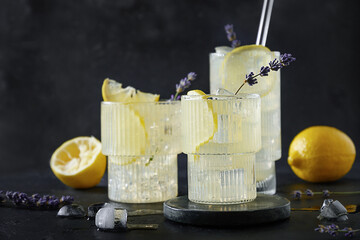 Cold lavender lemonade with lemon in glasses on black background. Summer drinks for freshness party.