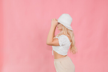 a young girl in a white hat and glasses poses on a pink background